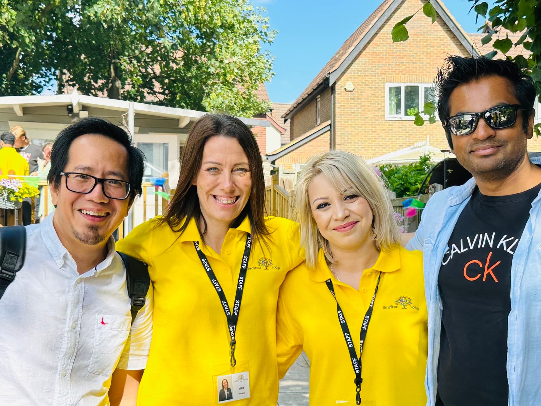 Four members of the Grafton Lodge team outdoors, two in yellow Grafton Lodge polo shirts